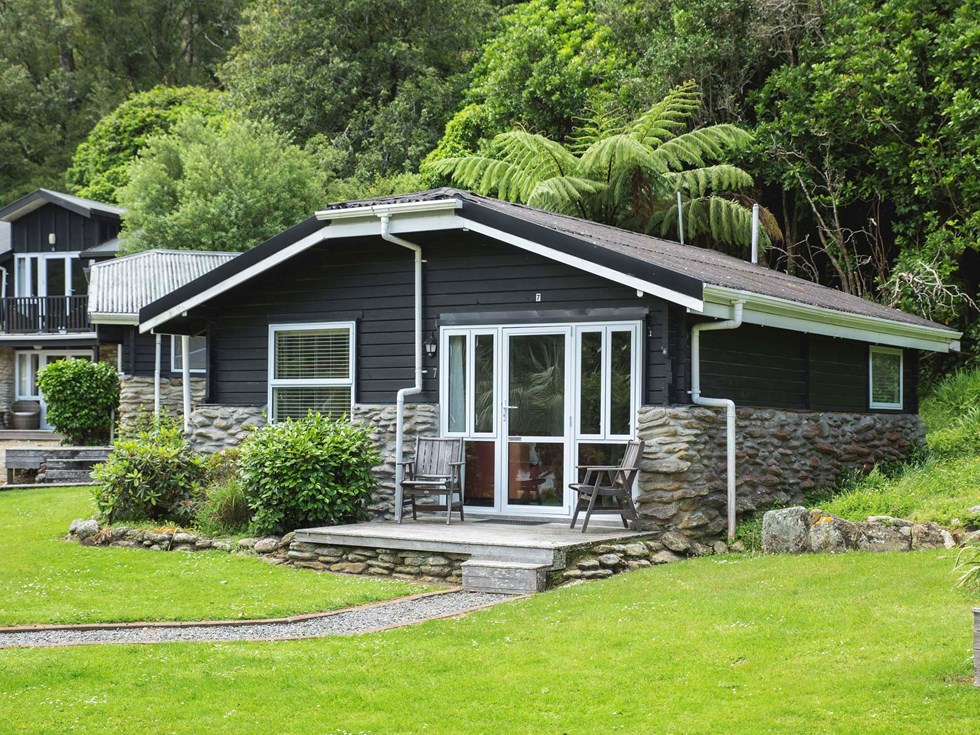 A Cook's Cottage surrounded by lush green native bush at Furneaux Lodge in the Marlborough Sounds at the top of New Zealand's South Island.