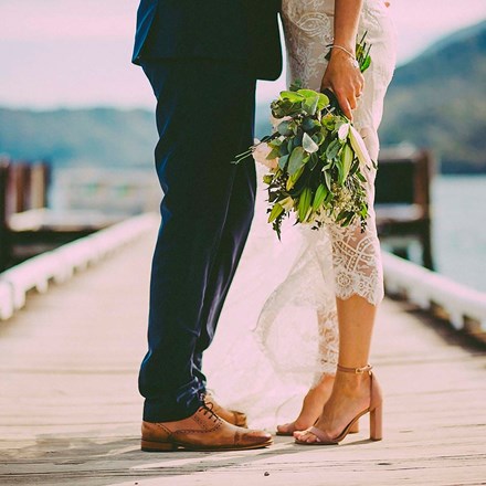 A newly married couple stand together on the Furneaux Lodge jetty in the Marlborough Sounds in New Zealand's top of the South Island