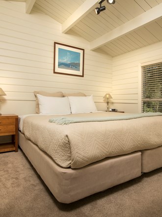 A Cook's Cottage bedroom with a king bed at Furneaux Lodge in the Marlborough Sounds, New Zealand.