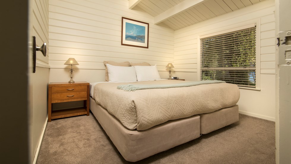 A Cook's Cottage bedroom with a king bed at Furneaux Lodge in the Marlborough Sounds, New Zealand.